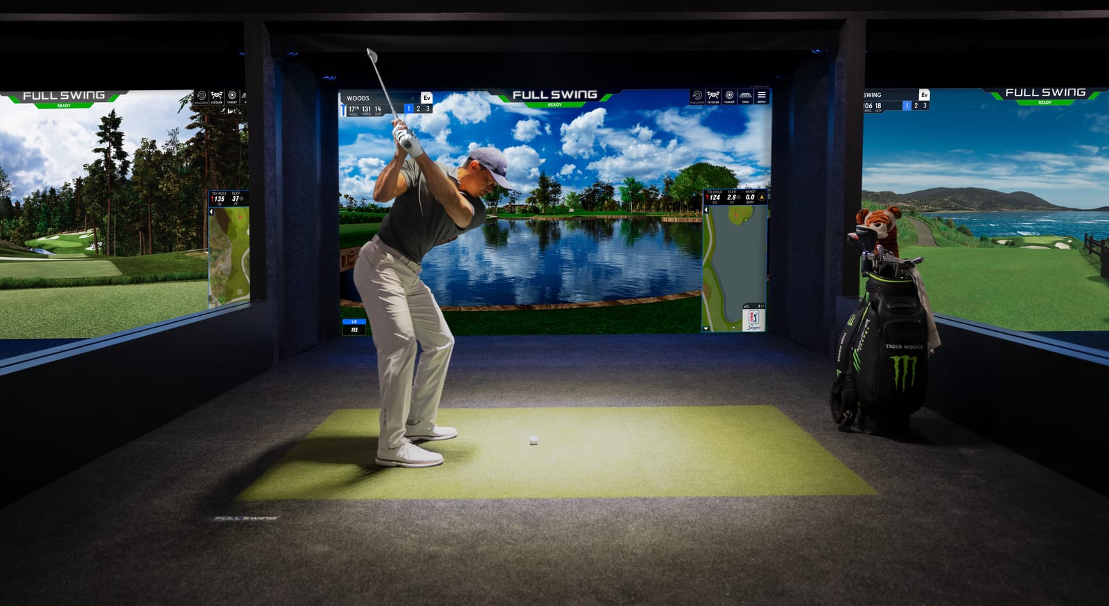 A golfer mid-swing in a Full Swing simulator bay